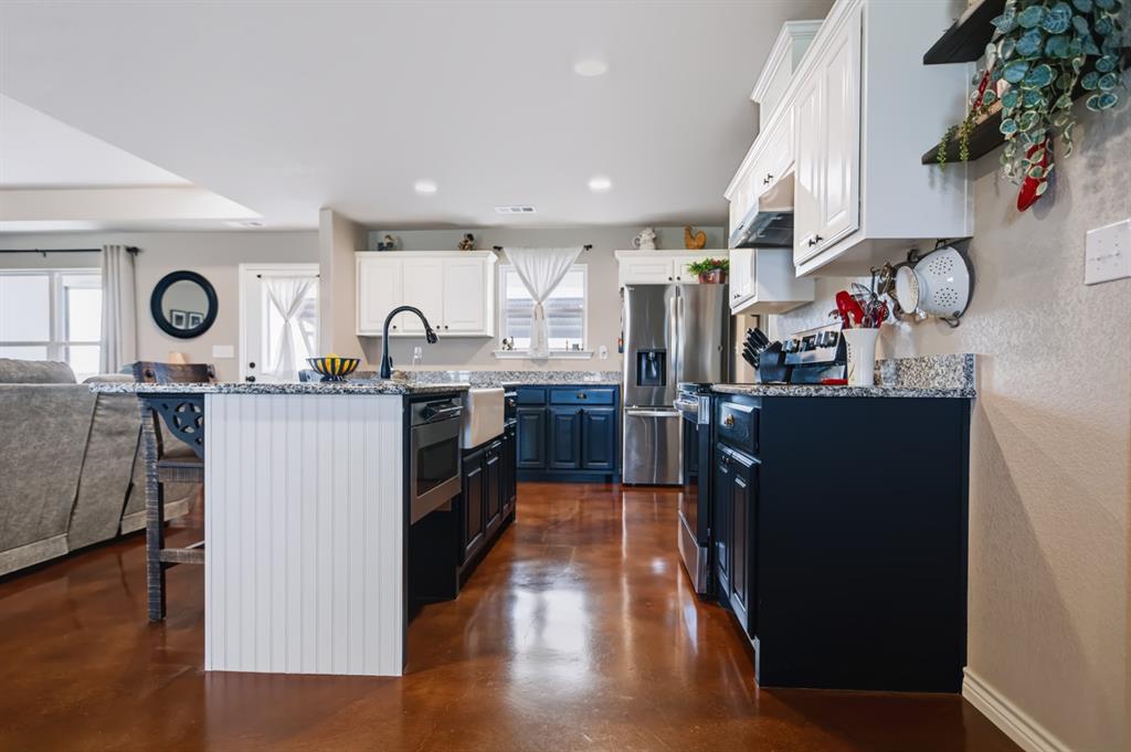 2433 Trlica Road West, TX 76691 - Photo 7 of 40 Kitchen with two-tone cabinetry, a central island, a farmhouse sink, stainless steel appliances, and a wood-finish floor