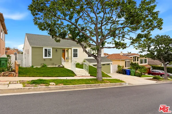 a front view of a house with a garden and tree