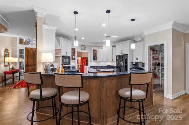 a kitchen with stainless steel appliances kitchen island granite countertop a dining table chairs and white cabinets