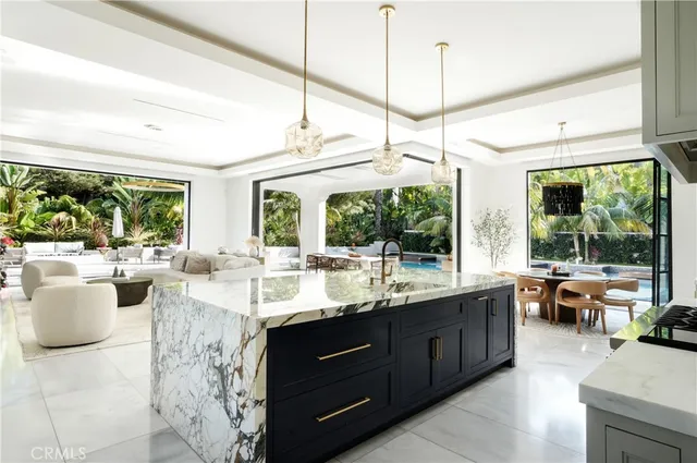 a large white kitchen with kitchen island a stove a sink a dining table and chairs