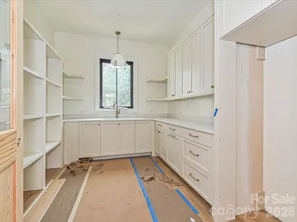 a kitchen with white cabinets and window