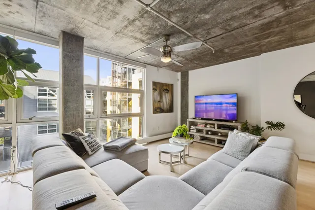 a living room with furniture a floor to ceiling window and a flat screen tv
