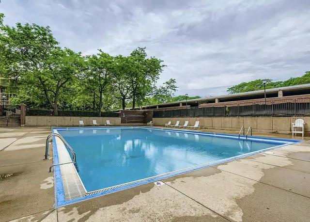 a view of swimming pool with seating space and trees in the background