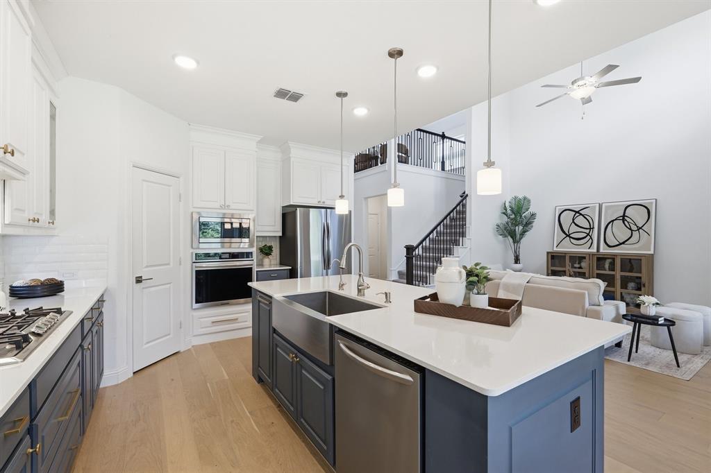 539 Farrell Lane Allen, TX 75013 - Photo 15 of 39 Open-concept kitchen featuring an oversized island with pendant lighting, stainless steel farmhouse sink, and a dishwasher