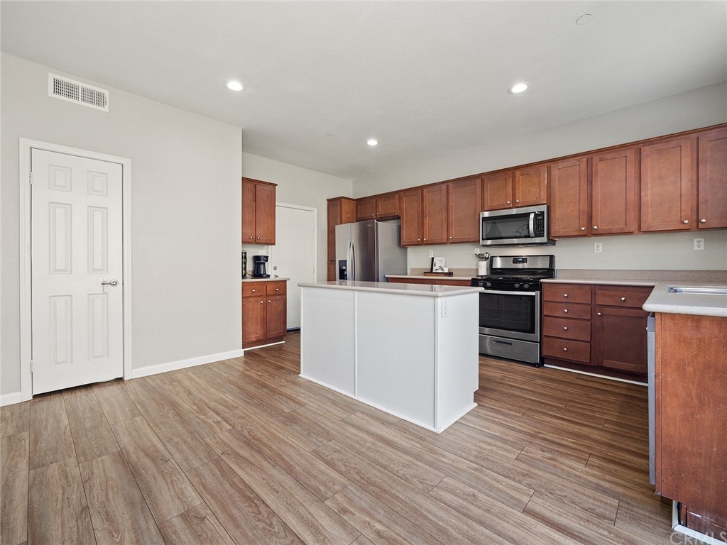 1779 Edmon Way Riverside, CA 92501 - Photo 13 of 63 a kitchen with wooden floors and white stainless steel appliances