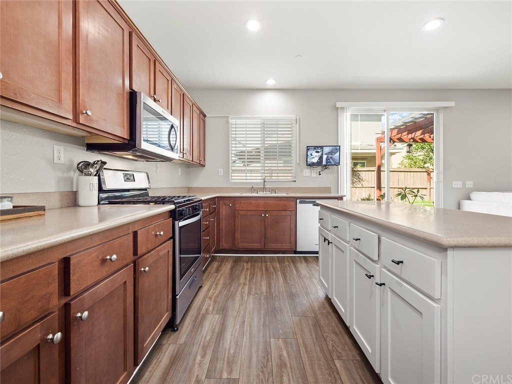 1779 Edmon Way Riverside, CA 92501 - Photo 14 of 63 a kitchen with stainless steel appliances granite countertop wooden cabinets a sink and dishwasher a stove with wooden floor