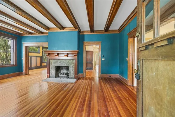 a view of an empty room with wooden floor and a window