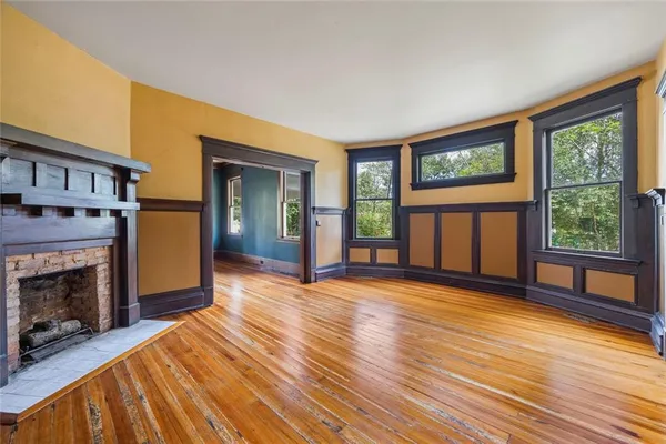 a view of an empty room with window and wooden floor