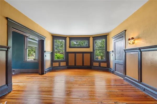a view of an empty room with wooden floor fireplace and a window