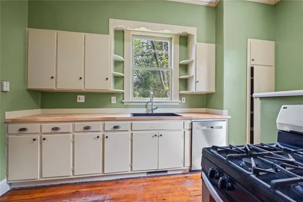 an empty room with wooden floor a ceiling fan and windows