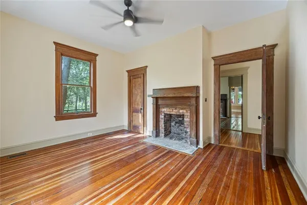 a view of a livingroom with wooden floor a ceiling fan and windows