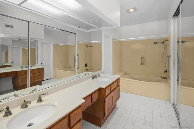a bathroom with a tub double sink shower and mirror