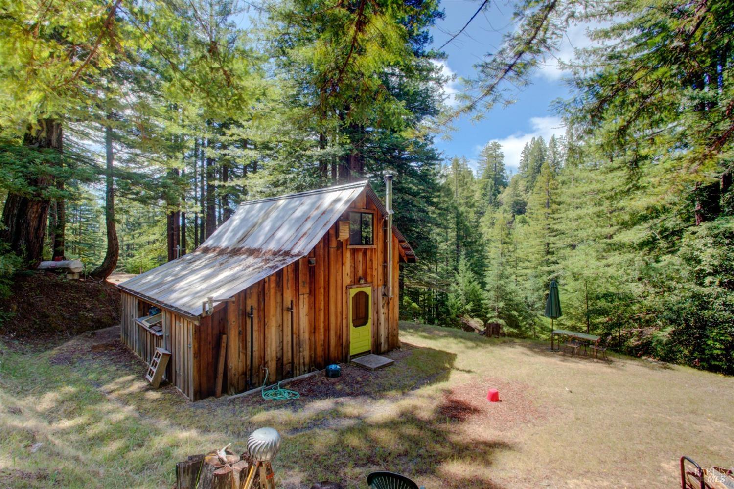 a backyard of a house with large trees and wooden fence