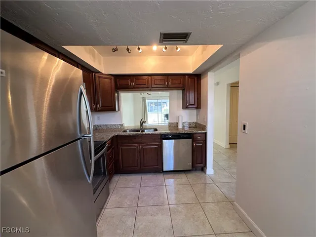 a kitchen with stainless steel appliances granite countertop a refrigerator a sink a stove and island