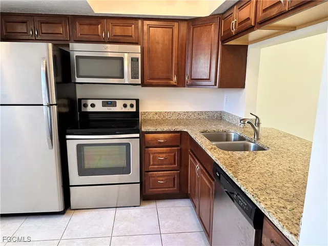 a kitchen with granite countertop a refrigerator stove and microwave