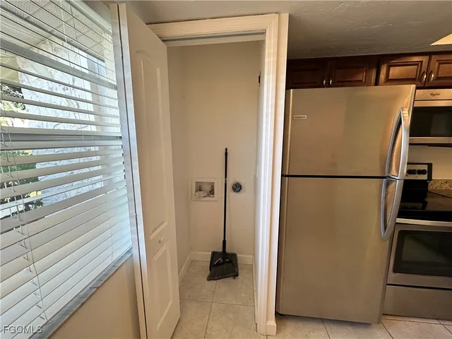 a view of a refrigerator in kitchen and an empty room