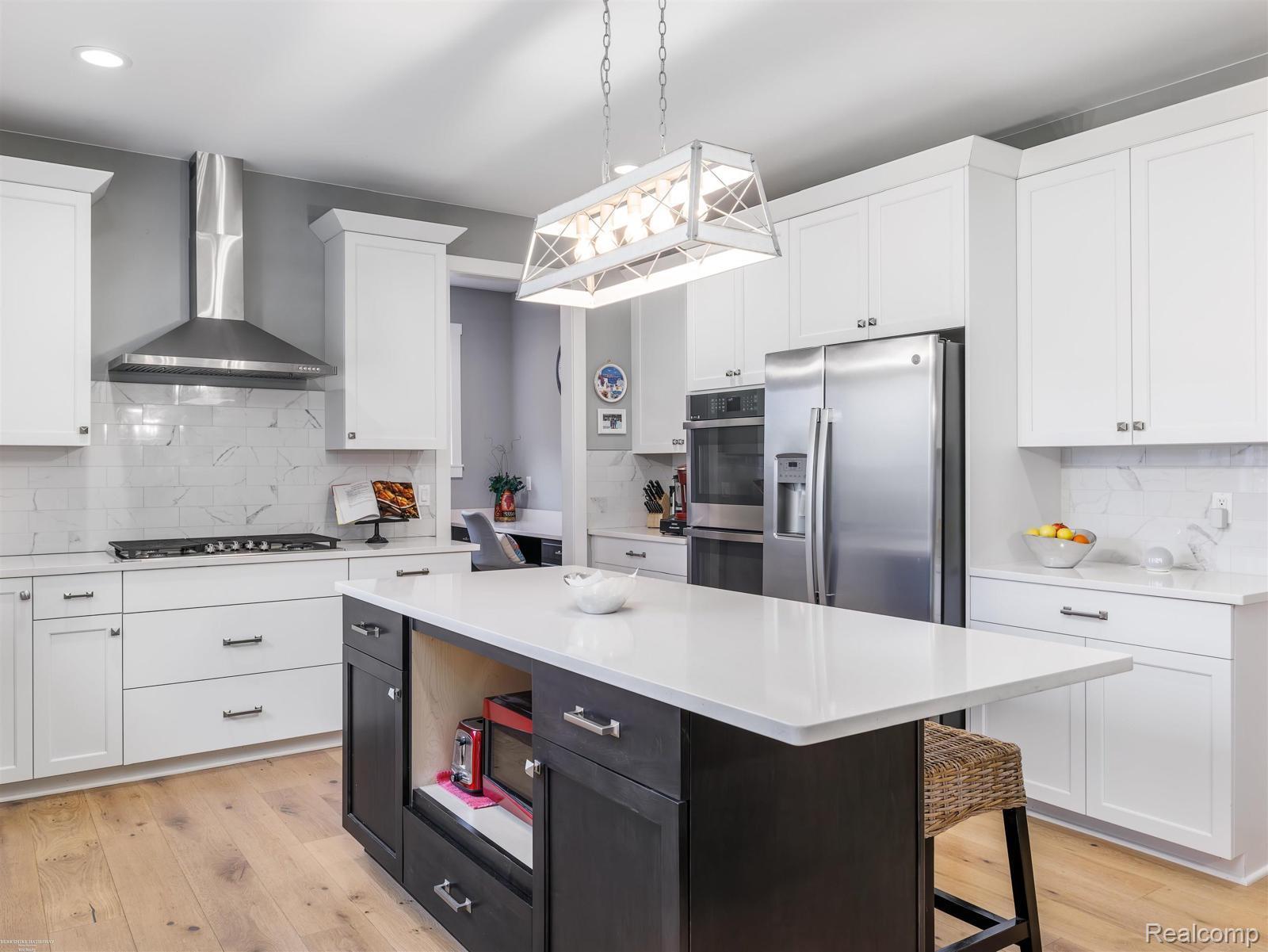 47705 Card Road Macomb, MI 48044 - Photo 12 of 53 Kitchen featuring a central island with white countertop, white upper and lower cabinetry, stainless steel appliances, and wood-finish flooring