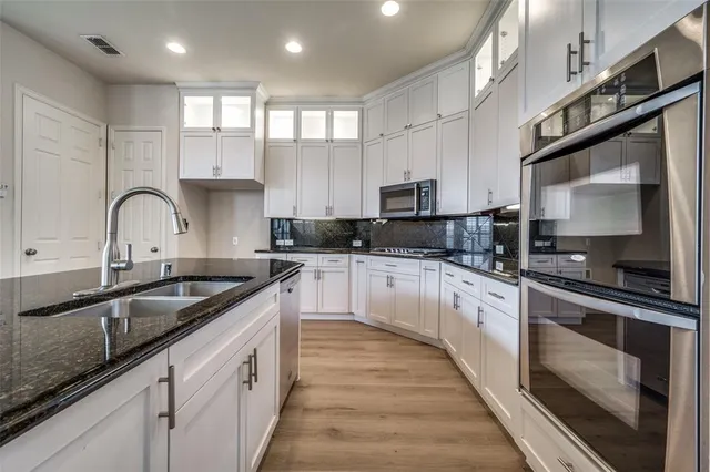 a large kitchen with stainless steel appliances granite countertop a sink a stove and cabinets