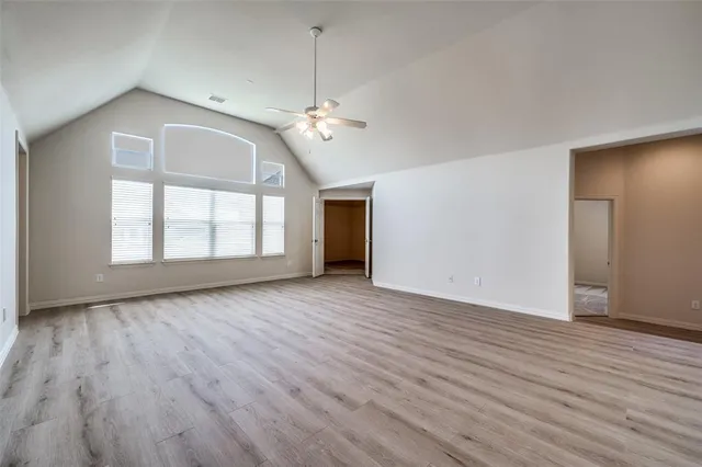 an empty room with wooden floor chandelier and windows
