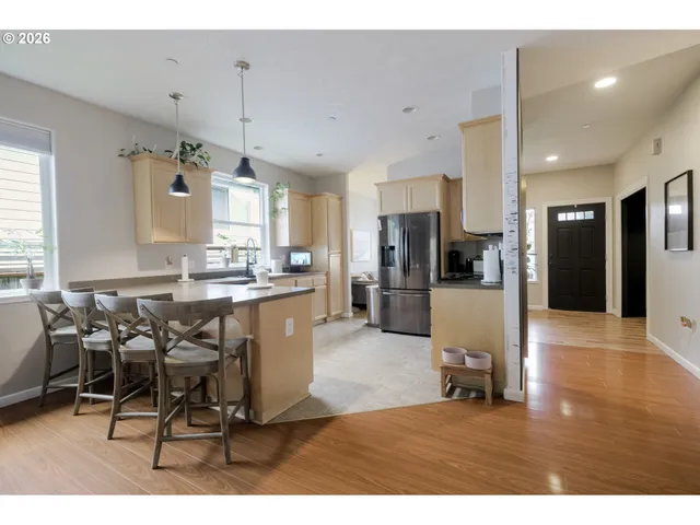 a kitchen with stainless steel appliances kitchen island granite countertop a refrigerator a stove a sink and white cabinets with wooden floor