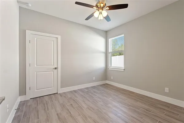 an empty room with wooden floor and a ceiling fan