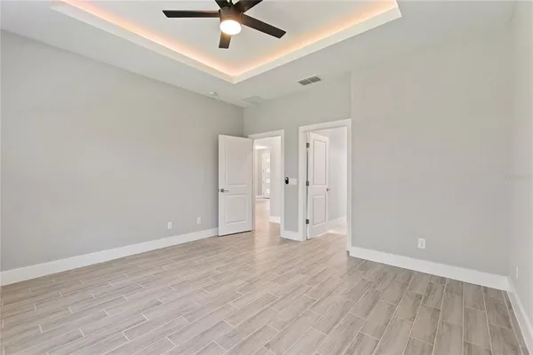 an empty room with wooden floor ceiling fan and windows