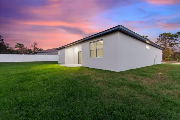 a front view of house with yard and trees in the background