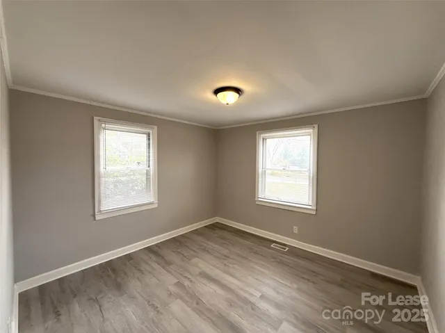 a view of an empty room with a window and wooden floor