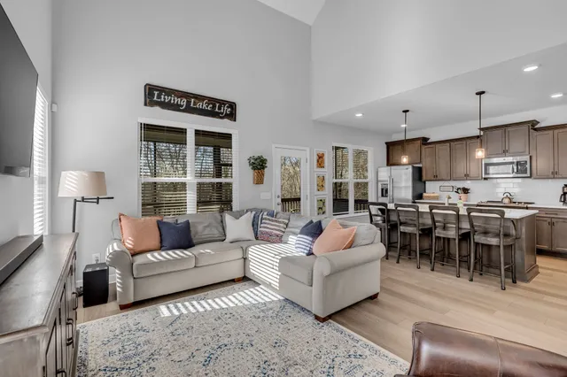 a kitchen with stainless steel appliances kitchen island granite countertop a dining table chairs sink and cabinets