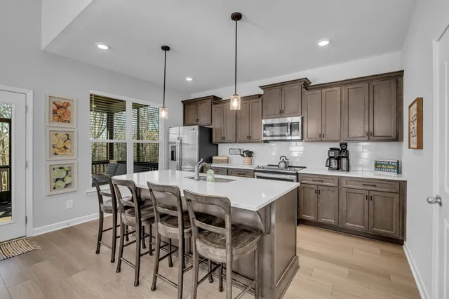 a kitchen with refrigerator a center island a stove and a refrigerator with wooden floor