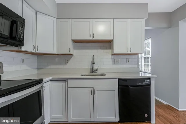 a kitchen with white cabinets and black appliances