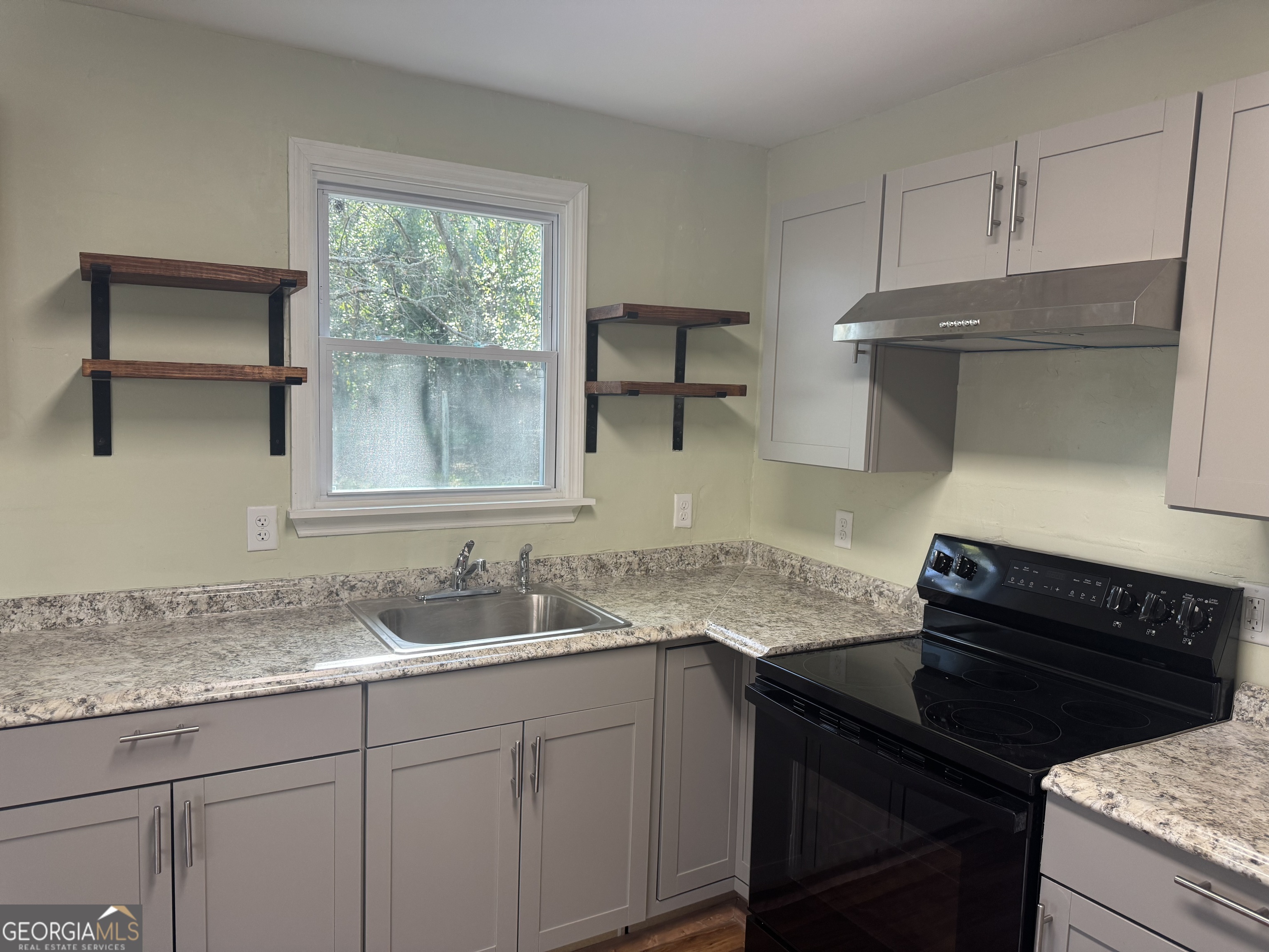 906 Central Avenue Dublin, GA 31021 - Photo 8 of 15 a kitchen with granite countertop a sink a stove and cabinets