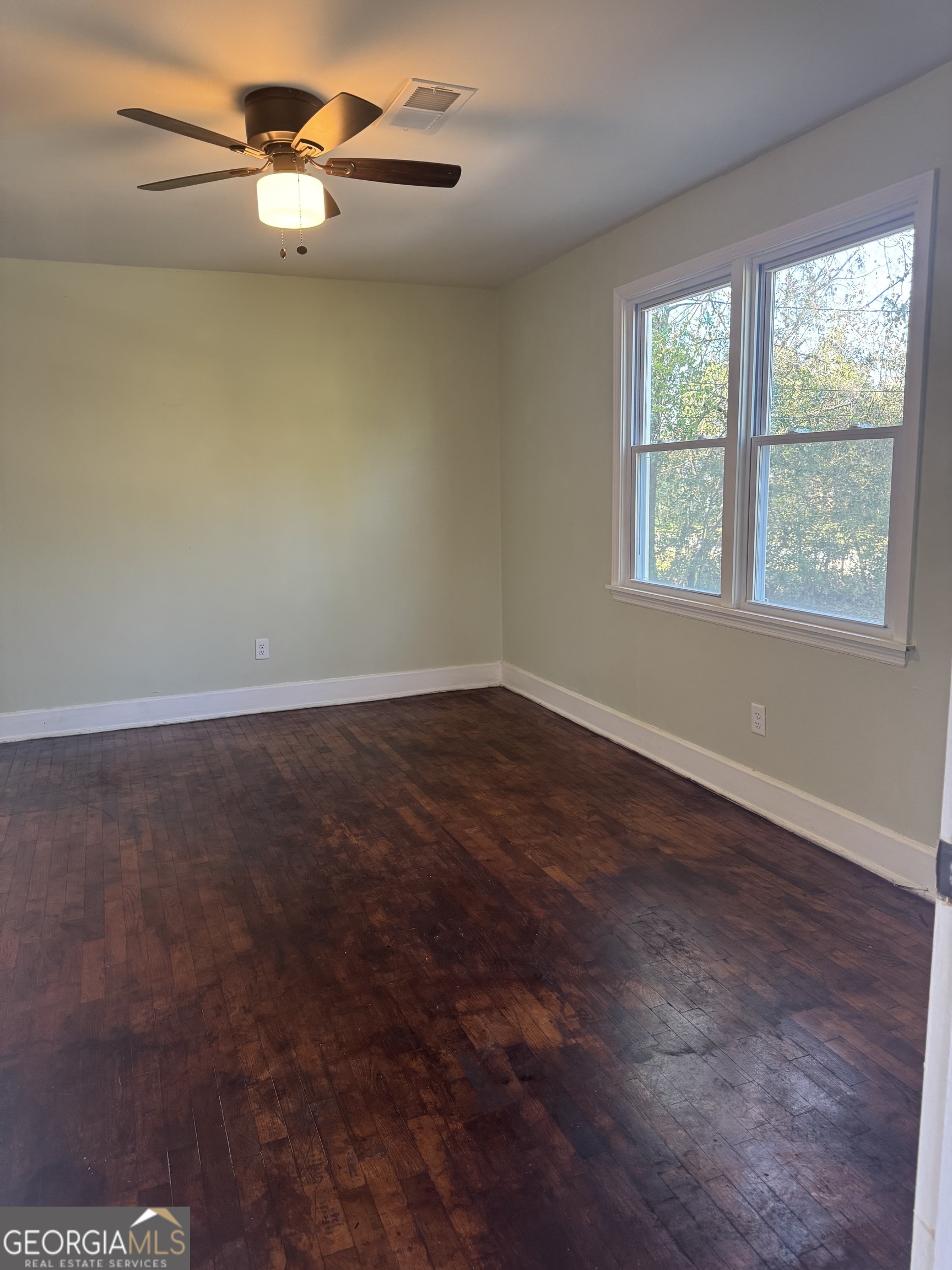 906 Central Avenue Dublin, GA 31021 - Photo 9 of 15 an empty room with wooden floor fan and windows