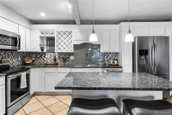 a kitchen with stainless steel appliances granite countertop a sink a stove a microwave a refrigerator and cabinets