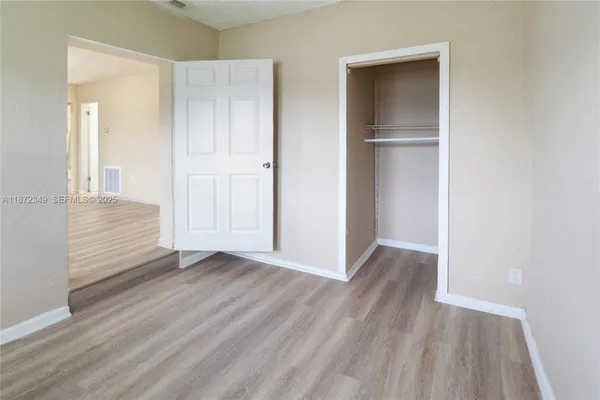 an empty room with wooden floor & closet