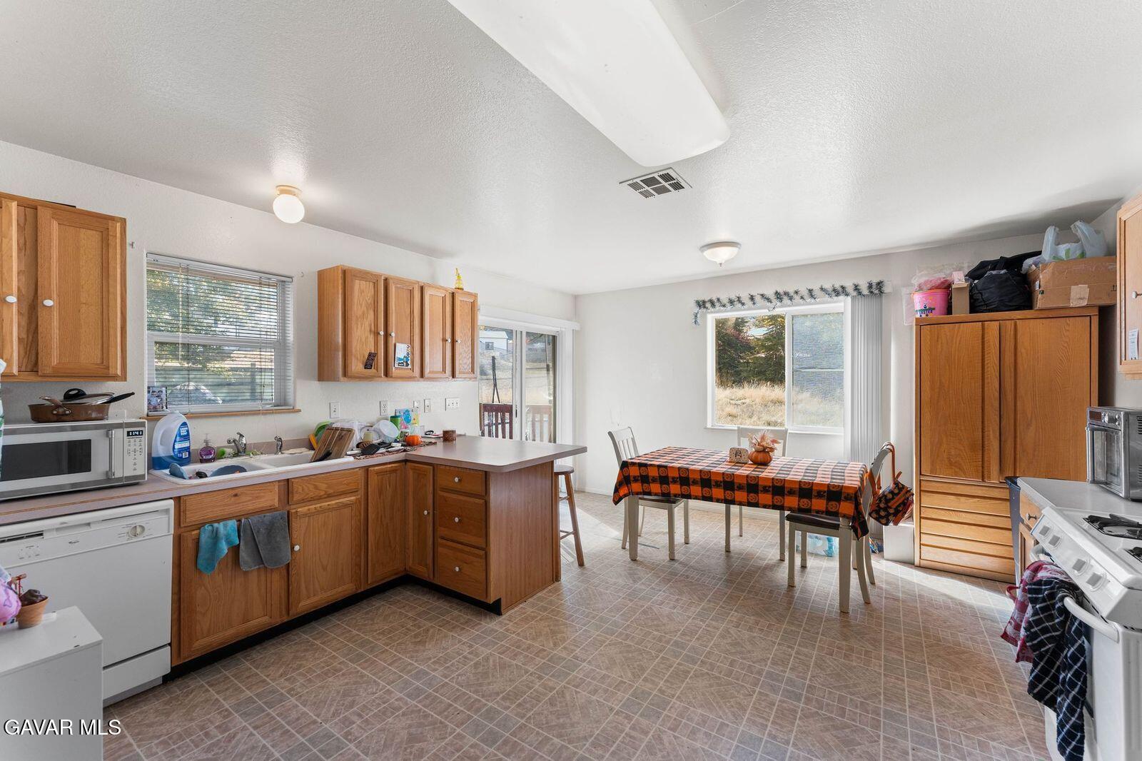 18330 Basil Drive Tehachapi, CA 93561 - Photo 16 of 47 a large white kitchen with a stove a sink dishwasher and cabinets with wooden floor