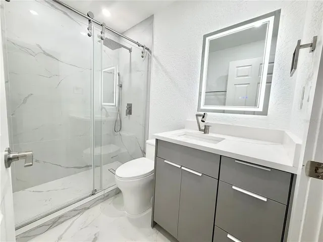 a bathroom with a shower sink vanity mirror and toilet
