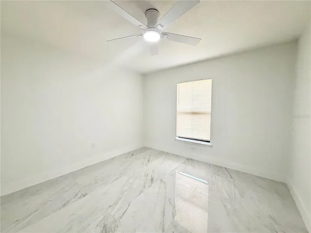 an empty room with a window and a fan