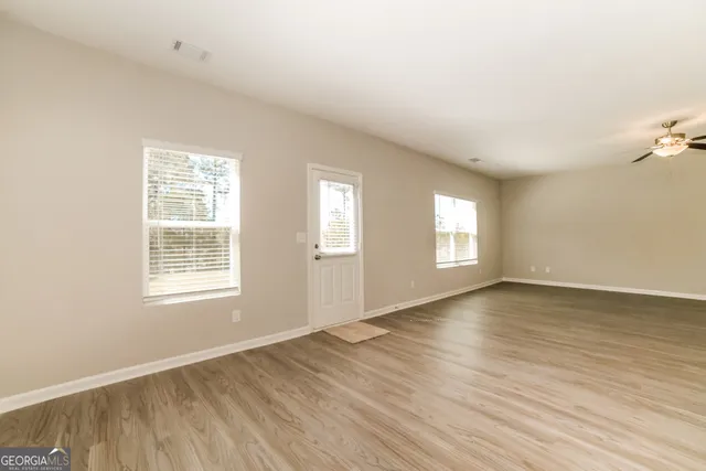 an empty room with wooden floor and windows