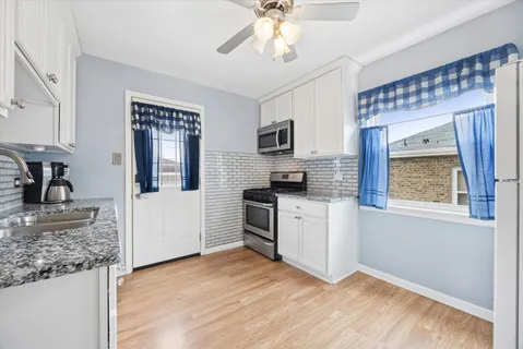 a kitchen with granite countertop a stove a sink and a microwave