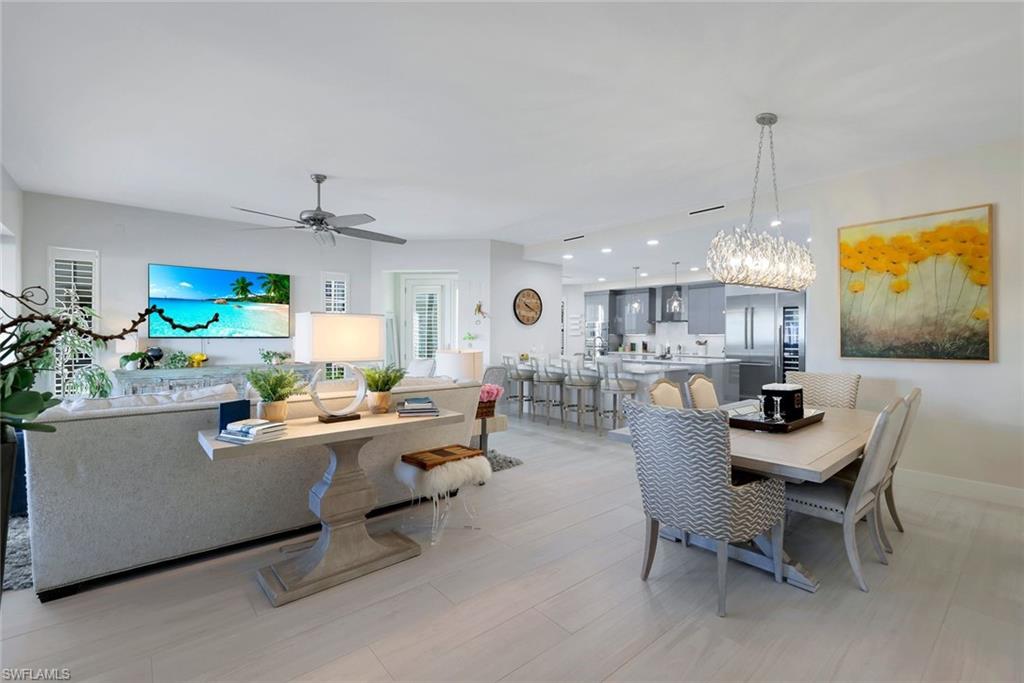 415 Sea Grove Lane, Unit 102 Naples, FL 34110 - Photo 11 of 36 a living room with furniture a chandelier and a dining table