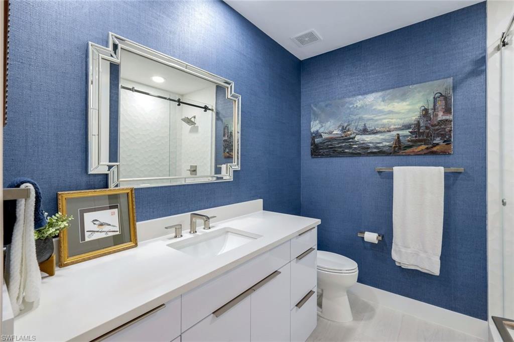 415 Sea Grove Lane, Unit 102 Naples, FL 34110 - Photo 17 of 36 a bathroom with a toilet a sink and mirror