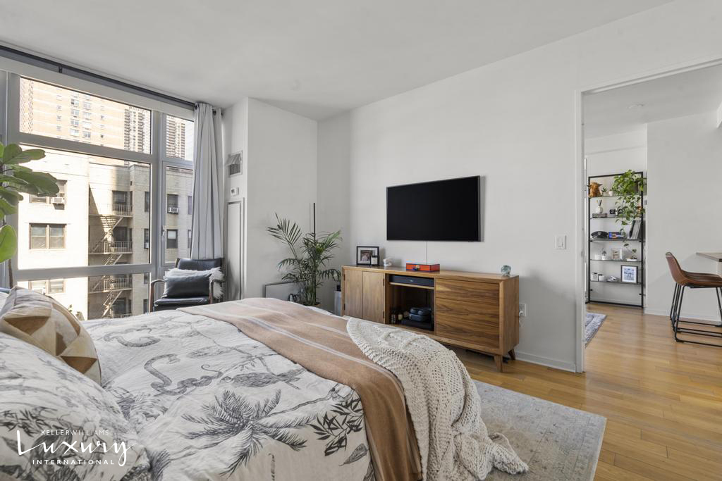 310 West 52nd Street, Unit 5J Manhattan, NY 10019 - Photo 9 of 16 a bedroom with a bed and a flat screen tv