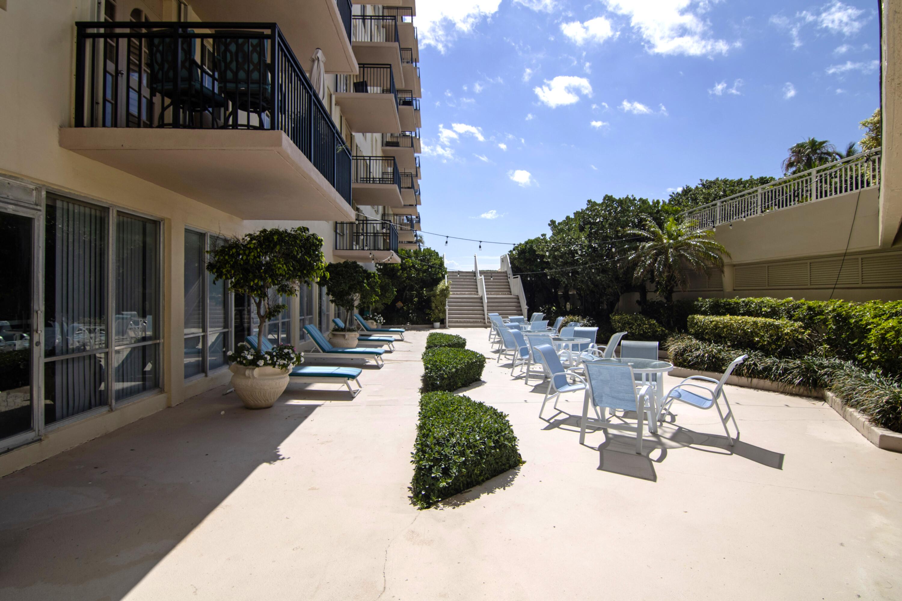 3475 South Ocean Boulevard, Unit 2160 Palm Beach, FL 33480 - Photo 45 of 54 a view of a patio with dining table and chairs with plants and palm tree