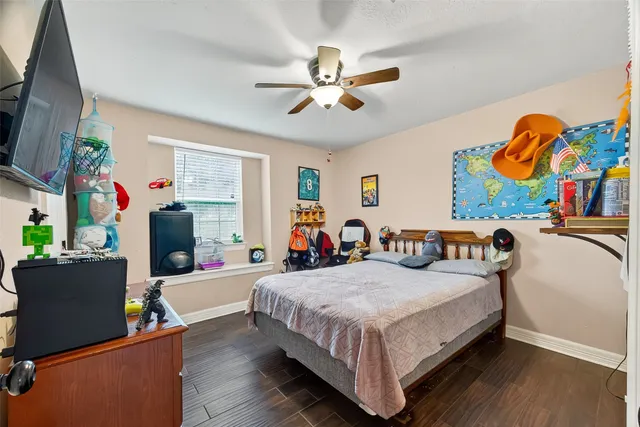 a bedroom with a bed and dresser with wooden floor