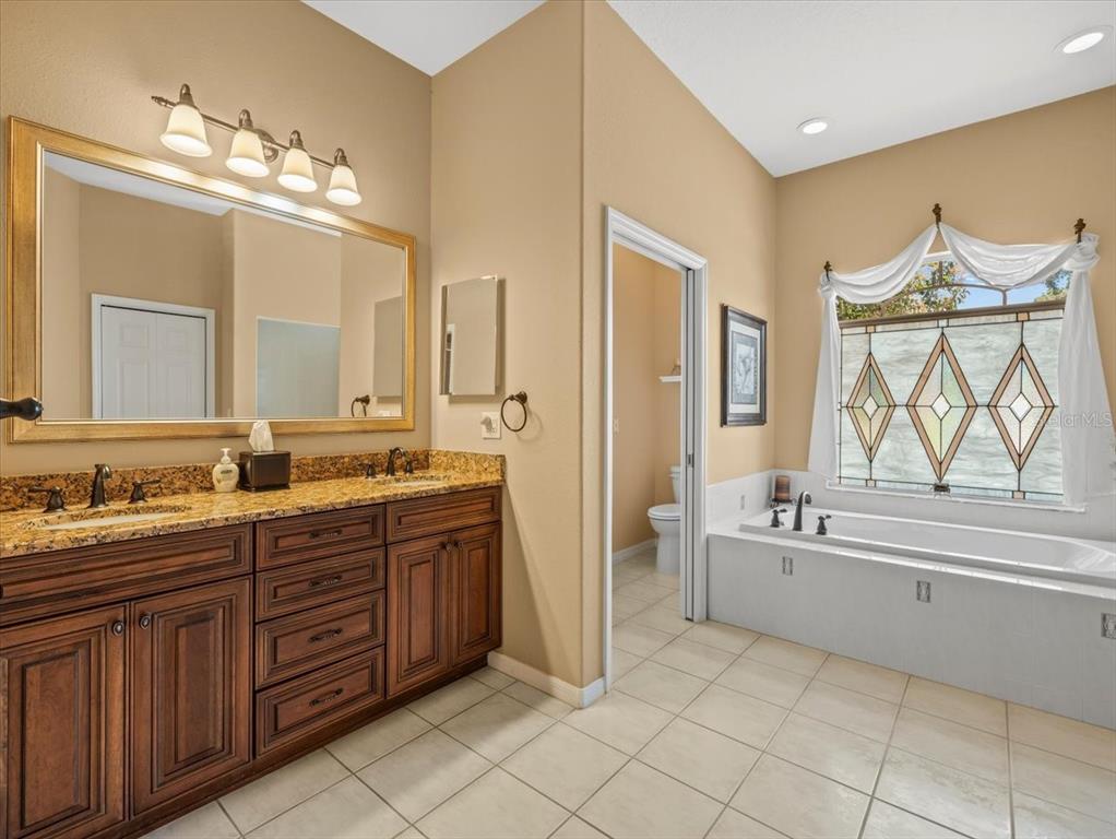 9216 Tarleton Circle Weeki Wachee, FL 34613 - Photo 20 of 66 a spacious bathroom with a double vanity sink a mirror a bathtub and next to a window