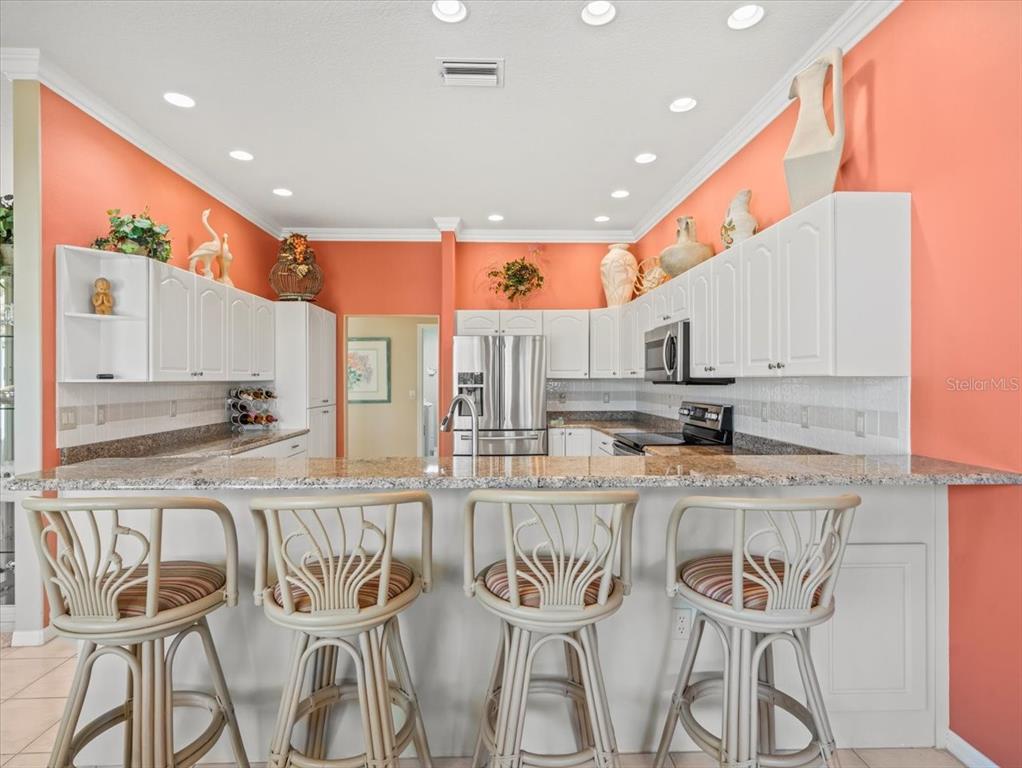 9216 Tarleton Circle Weeki Wachee, FL 34613 - Photo 30 of 66 a kitchen with stainless steel appliances kitchen island granite countertop a table and chairs in it