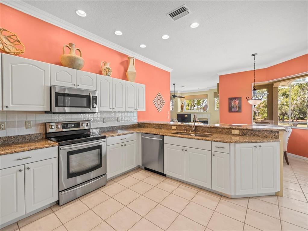 9216 Tarleton Circle Weeki Wachee, FL 34613 - Photo 35 of 66 a large kitchen with stainless steel appliances granite countertop a stove a sink and a microwave