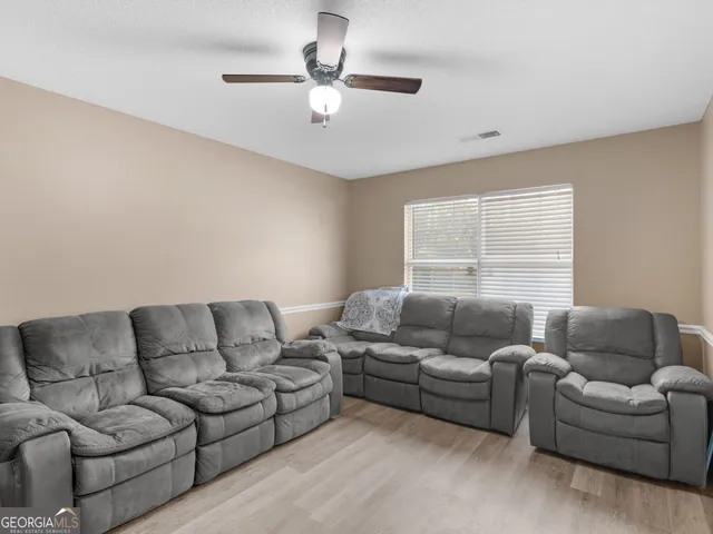 a living room with furniture a ceiling fan and a window