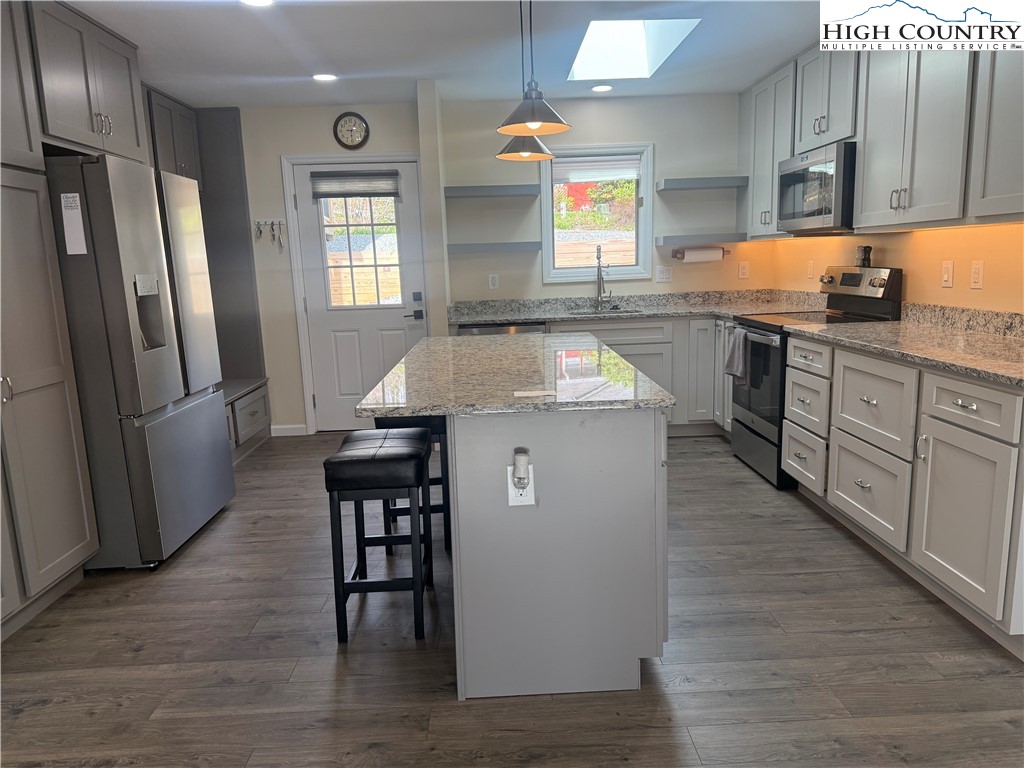 174 Spruce Pine Road Newland, NC 28657 - Photo 12 of 41 a kitchen with stainless steel appliances granite countertop a refrigerator a sink dishwasher a stove and white countertops with wooden floor